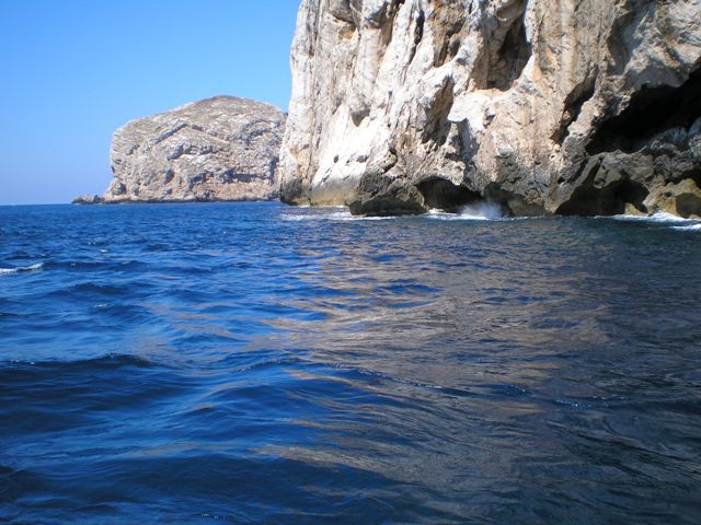 Lasciando le grotte, dalla nave, si puo' vedere la costa nelle vicinanze delle grotte lambita dalle acque azzurrissime, con le rocce che vi si specchiano dentro.